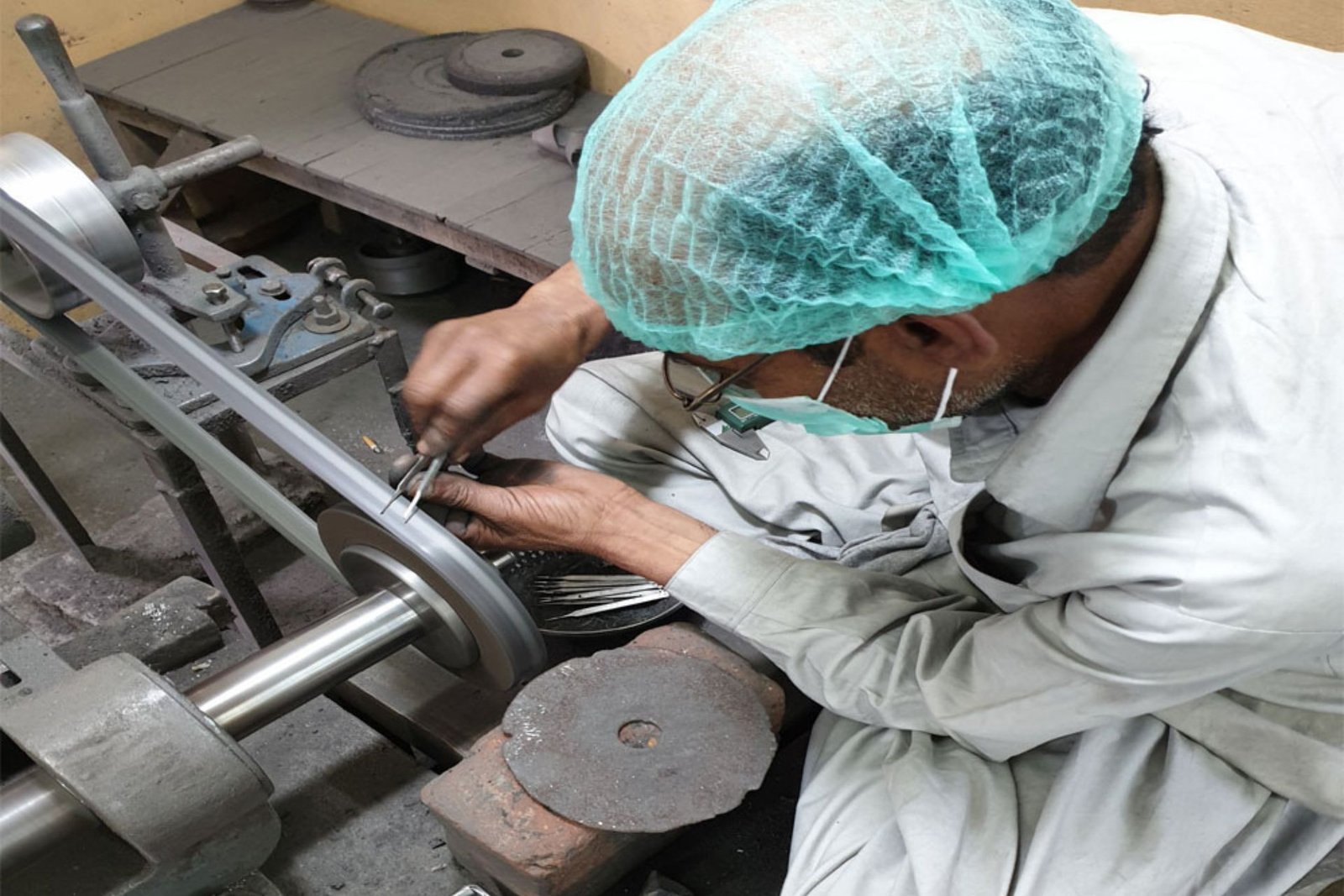 Artisan crafting precision stainless steel forceps on a grinding wheel to buy medical equipment online.